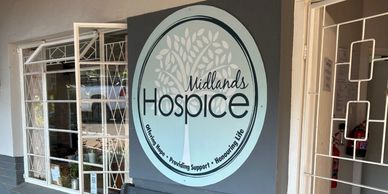 Entrance of Midlands Hospice with a welcoming sign and glass door.