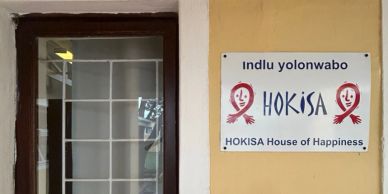 Signboard of HOKISA House of Happiness on a building wall.
