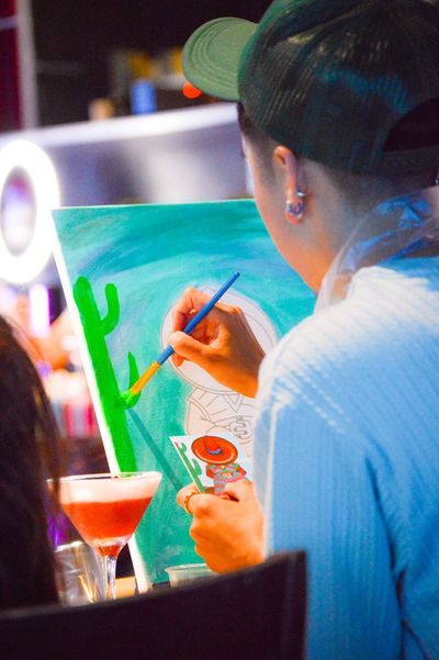Person painting a cactus on canvas.