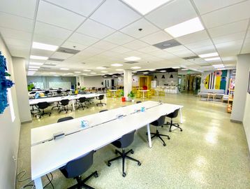 Modern office space with white work tables and black chairs and colorful abstract art decals