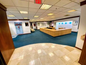 office recesption area with marble floors, blue carpet, and a large wood desk with a white ceiling