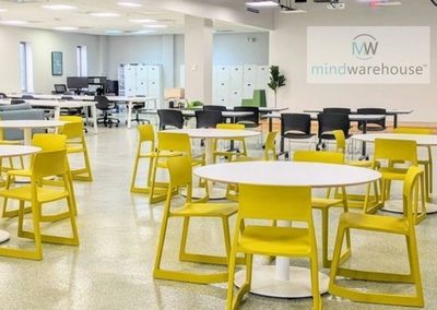 large business office with white tables and yellow screen. a logo for mindwarehouse appears on a scr