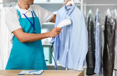 Person steaming a blue shirt in a laundry setting.