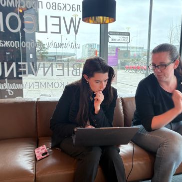 Two women working on a laptop in a cozy cafe.