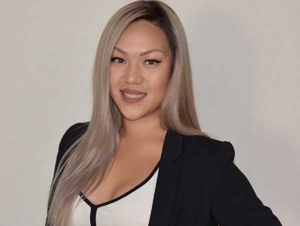 Confident woman with long blonde hair wearing a black blazer and white top.