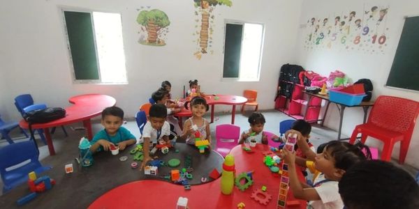 Children playing and building with blocks in a colorful classroom.