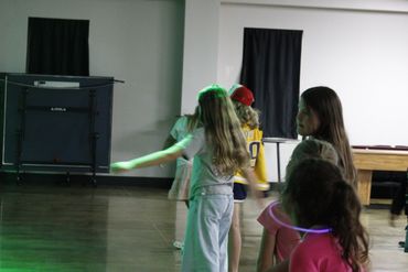 Children playing indoors with dim lighting and green light effects.