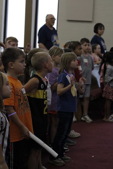 Children standing in a group indoors, engaged in an activity.