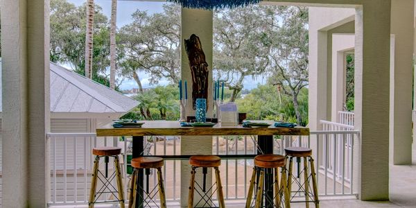 Live Edge Slab Wood Bar Leather Stools & Designer Rattan Chandelier on bayfront balcony