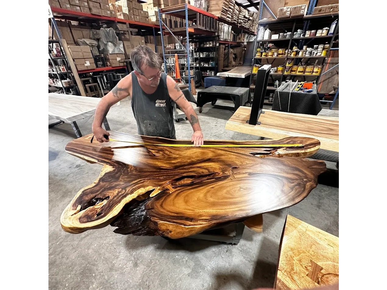 A Decor Direct Fabricator measuring a curvaceous live edge wood slab for a rustic mod executive desk