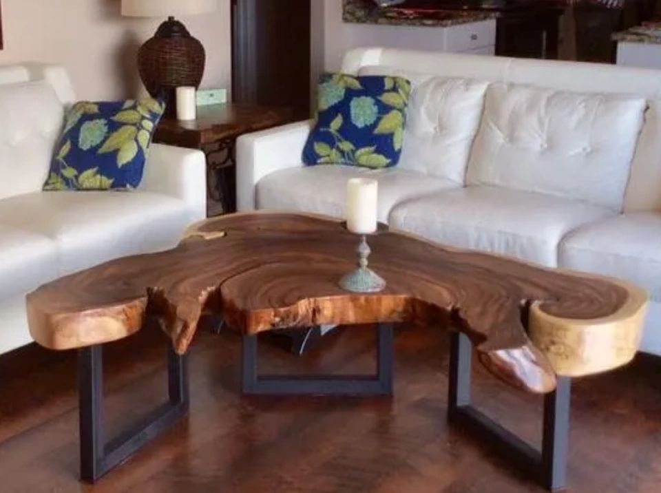 Live Edge Coffee table with 3 iron legs pictured in living room by white sofa and tropical setting. 