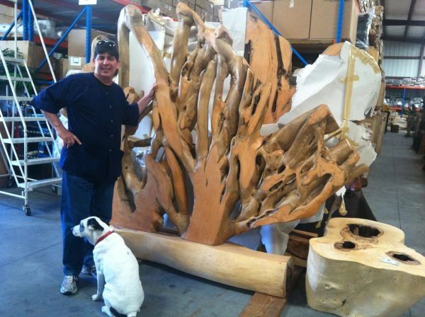 Rustic teak root art sculpture room divider mounted on log in warehouse with designer and dog