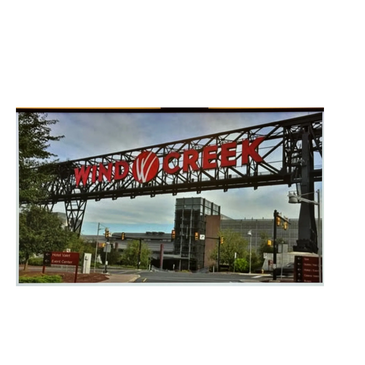 Entrance sign for Wind Creek over a street with buildings and traffic lights.