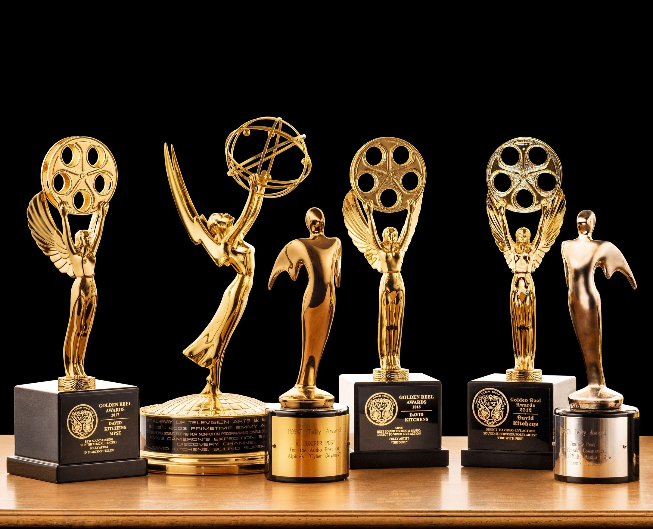 Golden film and television awards displayed on a wooden surface.