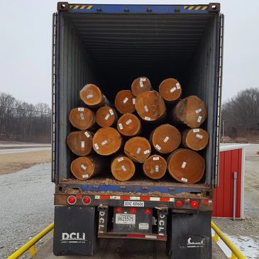 Logs stacked inside a shipping container on a truck.