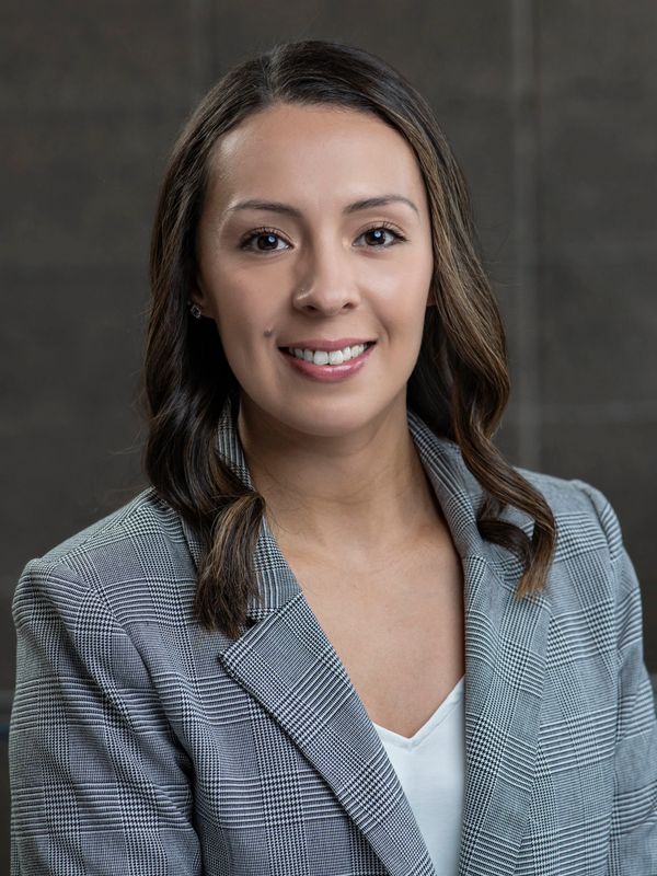 Professional woman in a gray plaid blazer smiling confidently.