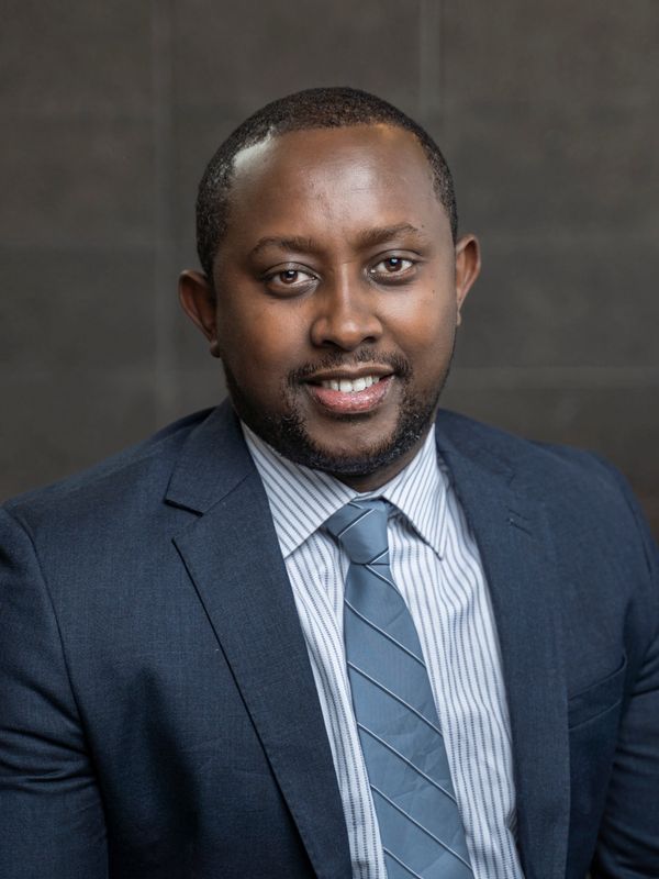 Professional man in a blue suit and striped tie smiling at the camera.