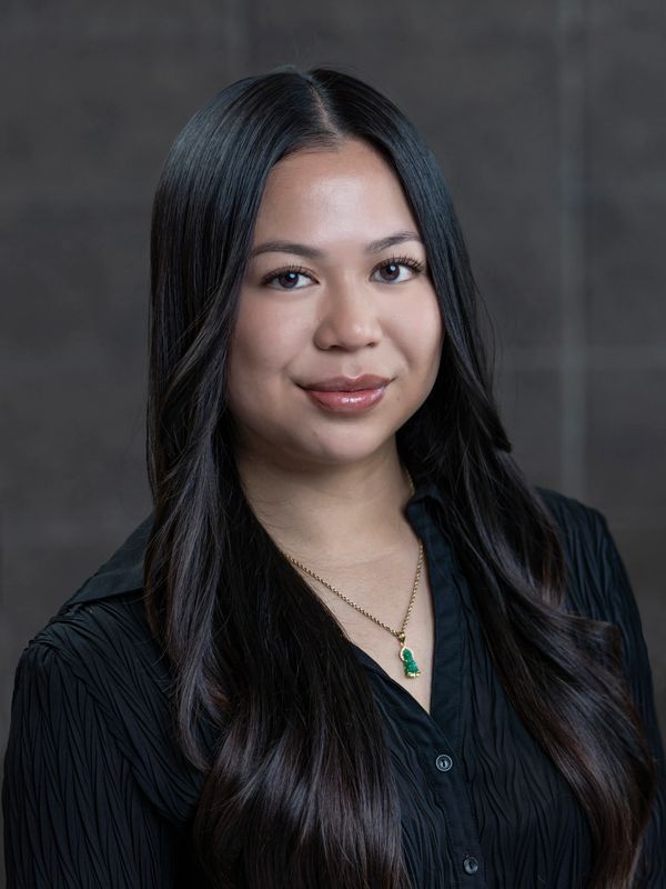 Portrait of a young woman with long black hair and a green pendant necklace.