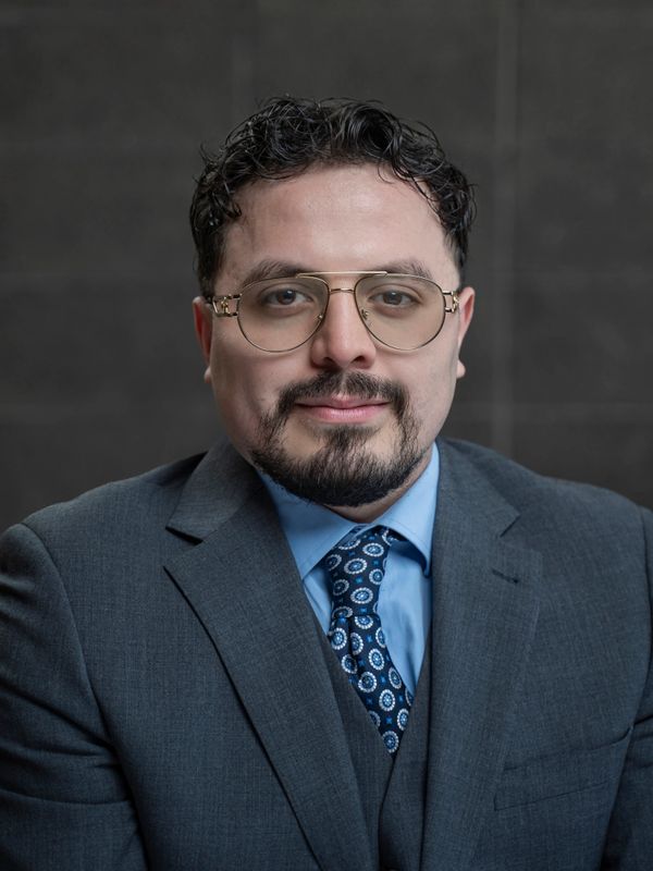 Professional man in glasses and a suit with a patterned tie.