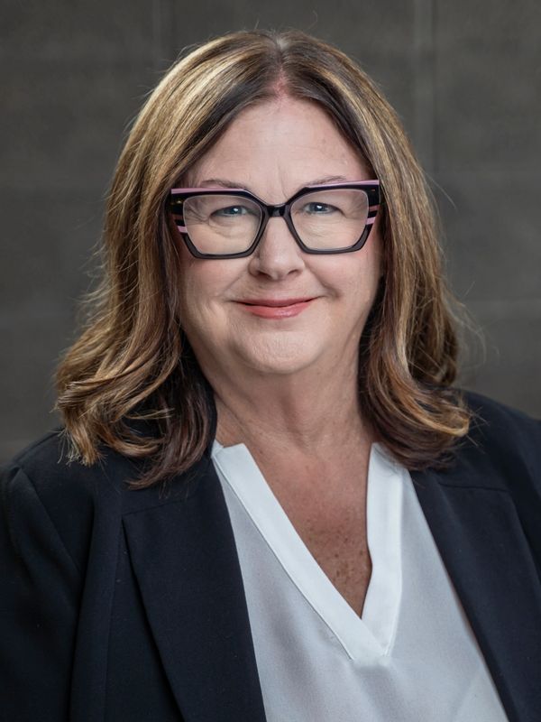 Professional woman with glasses smiling in a business portrait.