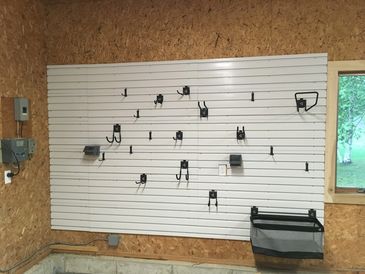 White wall in garage with hooks and a basket hanging 