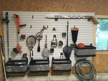 White wall in garage with hooks and a basket hanging 
