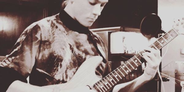 Person playing electric guitar in a cozy room.