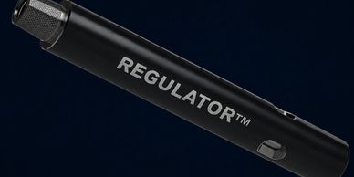 Close-up of a black REGULATOR™ device against a dark background.