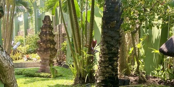 Lush garden with tropical plants and a stone sculpture.