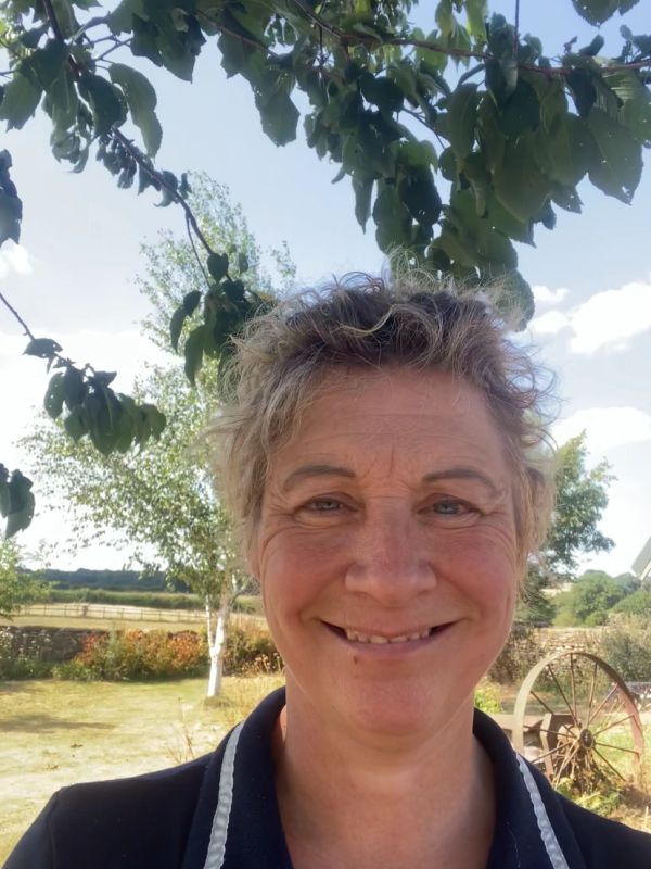 Smiling woman outdoors under a tree.