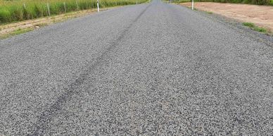 A freshly paved gray asphalt road stretching into the distance.