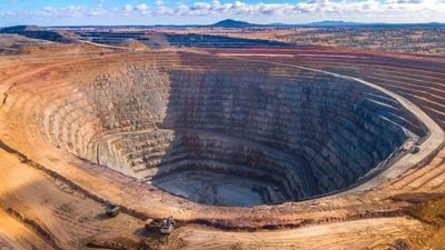 A large open-pit mine with terraced sides under a blue sky.