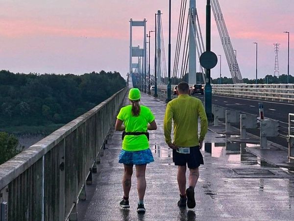 Two people walking on a bridge at dusk.