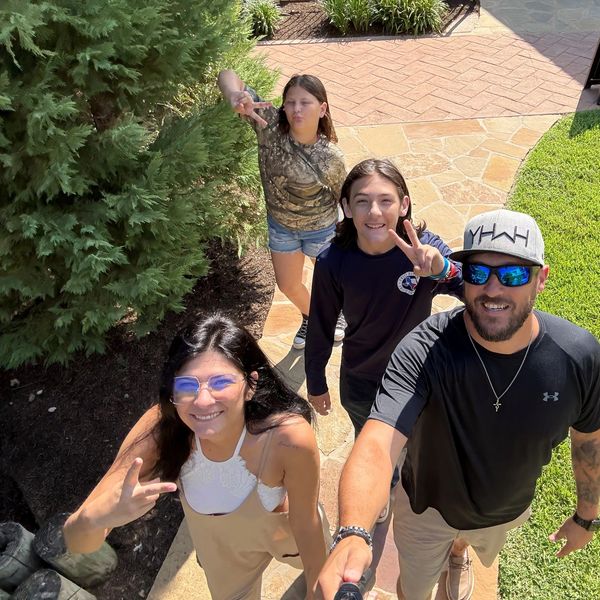 Group of four people making peace signs outdoors.