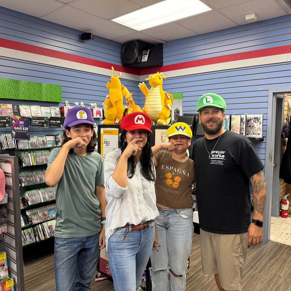 Four people wearing Mario-themed hats inside a game store.