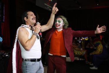 Two men, one dressed as Freddie Mercury and the other as Joker, enjoy a lively event.