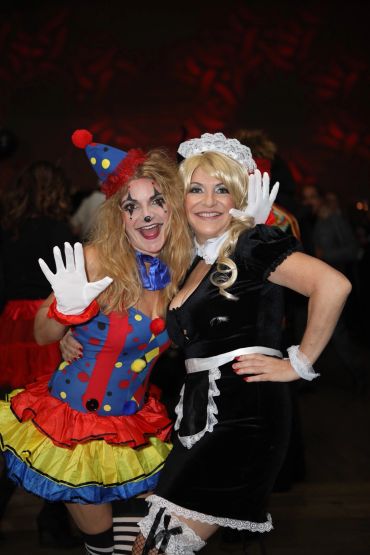 Two women in colorful costumes posing and smiling.