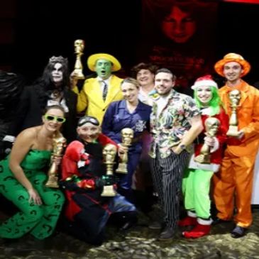 Group dressed in colorful costumes holding trophies.