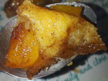 Peach cobbler rolls held on a spoon