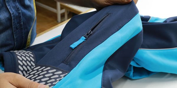 Hands holding a blue and navy jacket with a zipper detail.