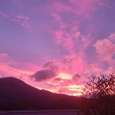 Pink and purple sunset sky over mountain silhouette.