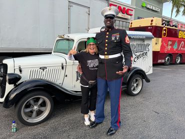 Debbie from Karmic Ice Cream and a Marine stand in front of the 1935 Karmic Ice Cream truck