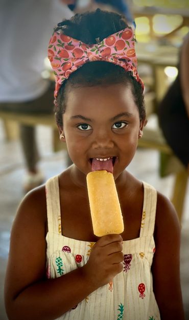 Young girl eating pineapple Karmic Ice Pop from Ice Cream cart in Miami Beach