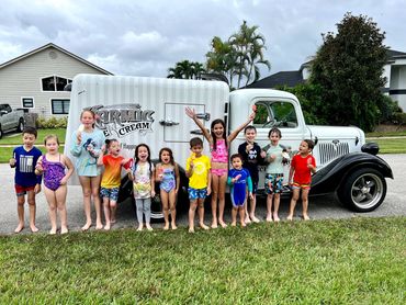 A group of children stand along side the 1935 Karmic Ice Cream truck