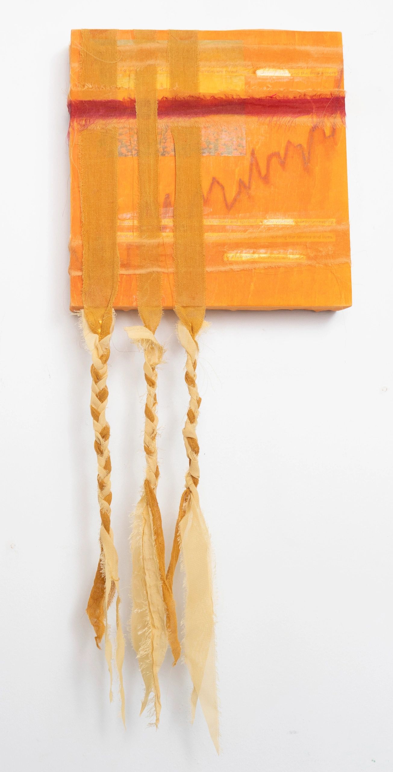 Orange textile art with three hanging braided strips.