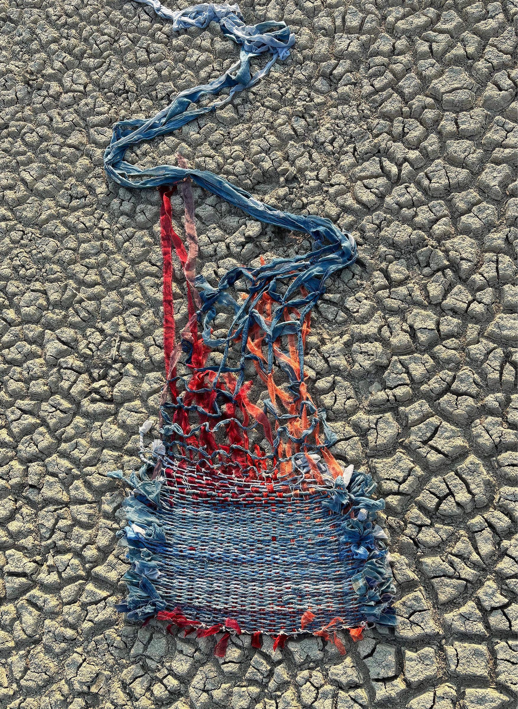 Woven fabric on cracked dry ground.