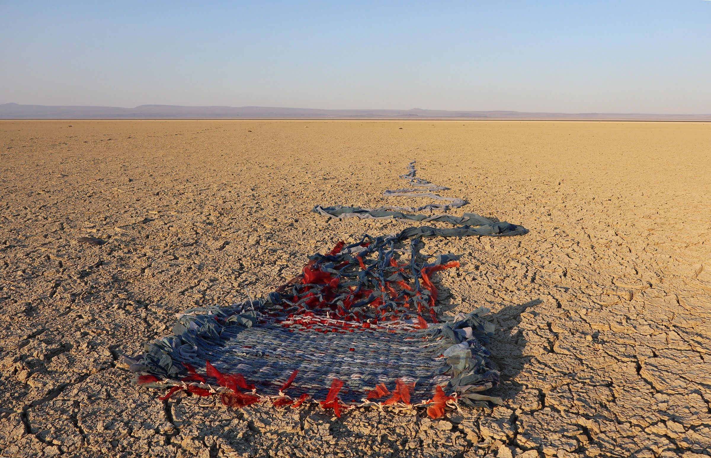Woven fabric strip on cracked desert ground.