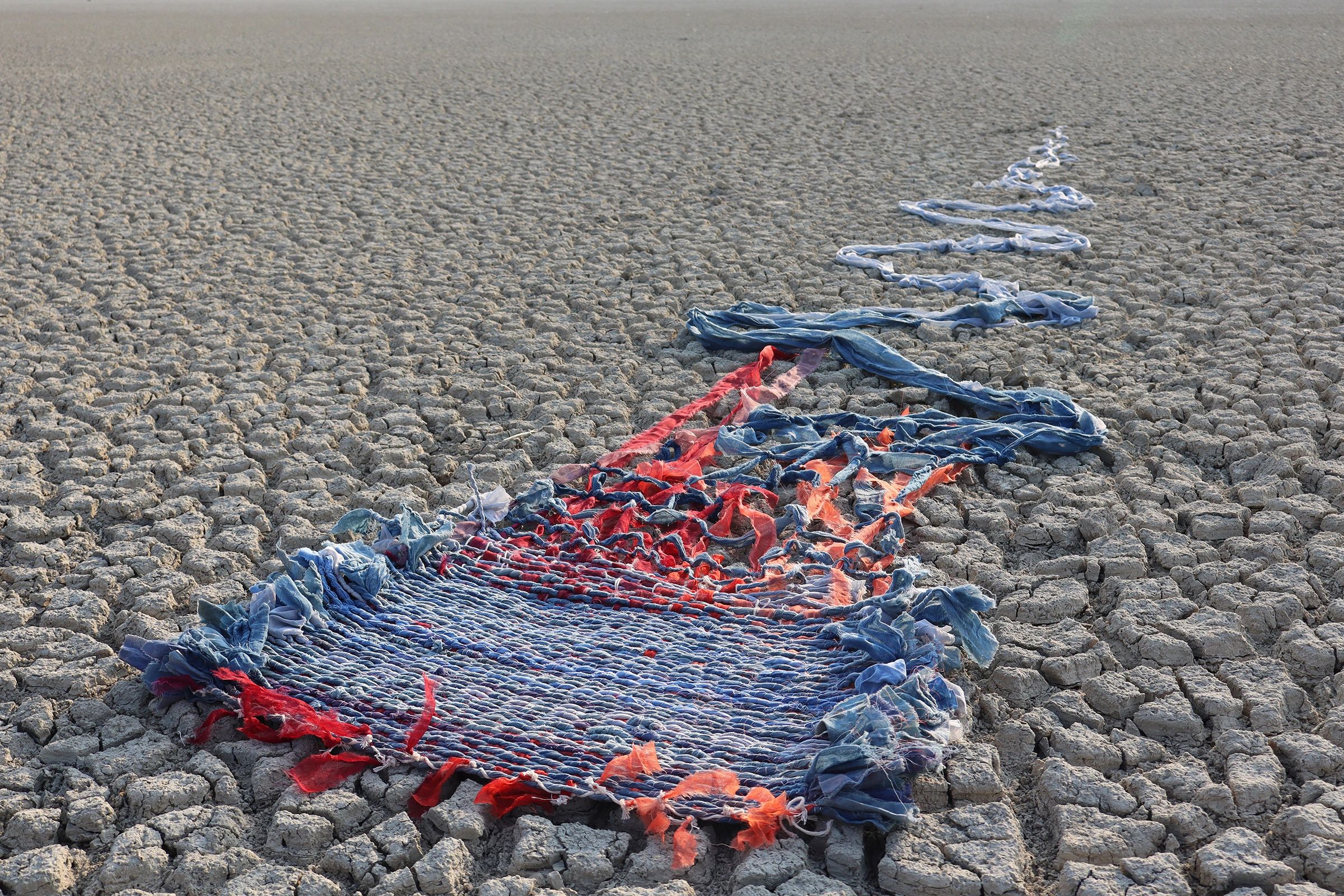 Colorful knitted fabric on dry cracked earth.