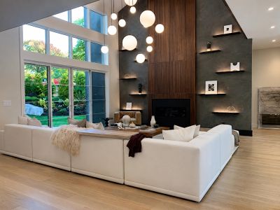 Modern living room with white sectional sofa and hanging globe lights.