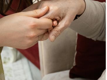 A younger hand gently holding an elderly hand in a comforting gesture.